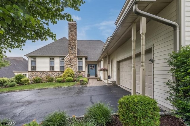 22 Troon Dr, Fredon Twp, NJ 07860 - view of front facade featuring asphalt driveway, an attached garage, a chimney, and stone siding