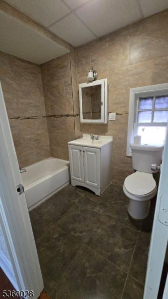 152 Ivy St, Newark City, NJ 07106 - bathroom featuring toilet, vanity, a bath, a paneled ceiling, and tile walls