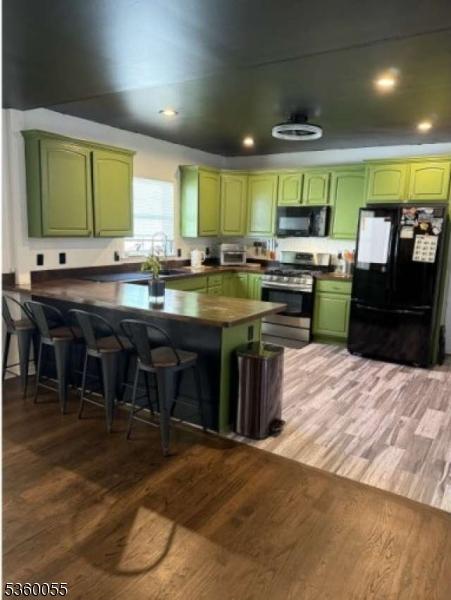 284 W Webster Ave, Roselle Park Boro, NJ 07204 - kitchen featuring green cabinetry, black appliances, light wood finished floors, a breakfast bar area, and recessed lighting