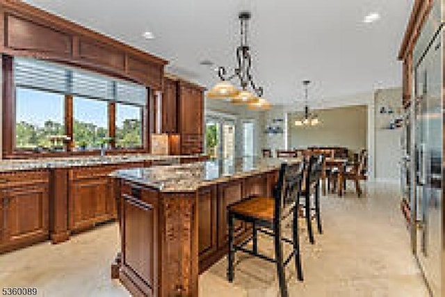 2 Kristina Way, Raritan Twp, NJ 08822 - kitchen with a kitchen island, decorative light fixtures, brown cabinets, a kitchen breakfast bar, and a chandelier