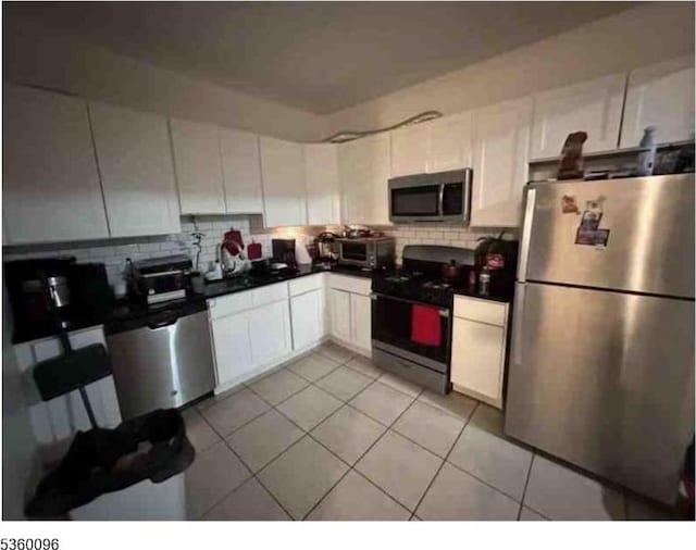 85 Tillinghast St, Newark City, NJ 07108 - kitchen featuring stainless steel appliances, backsplash, light tile patterned floors, and white cabinetry