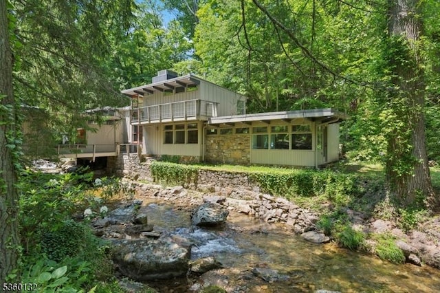 63 Hollow Brook Rd, Tewksbury Twp, NJ 07830 - back of house featuring stone siding, a chimney, a balcony, and a view of trees