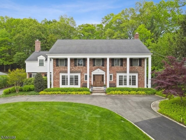 70 Falmouth St, Millburn Twp, NJ 07078 - greek revival inspired property with a chimney, asphalt driveway, brick siding, and a front lawn