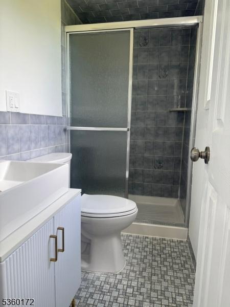 20 Wick Dr, Woodbridge Twp, NJ 08863 - bathroom with toilet, a stall shower, vanity, tile walls, and tile patterned floors