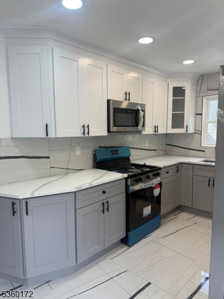 20 Wick Dr, Woodbridge Twp, NJ 08863 - kitchen featuring stainless steel microwave, range with gas cooktop, gray cabinets, glass insert cabinets, and tasteful backsplash