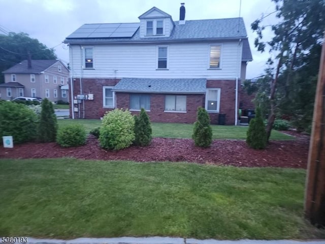 20 Harrison St, Nutley Twp, NJ 07110 - back of property featuring brick siding, roof mounted solar panels, a lawn, and a chimney