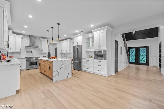 10 Wilson Ave, Wayne Twp, NJ 07470 - kitchen with wall chimney range hood, high quality appliances, light wood-type flooring, backsplash, and white cabinets