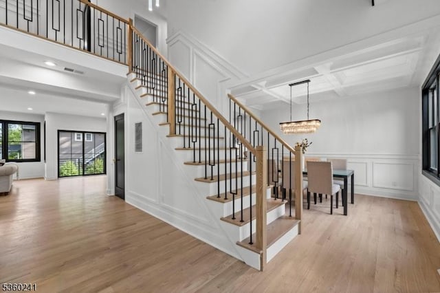 10 Wilson Ave, Wayne Twp, NJ 07470 - stairway featuring a decorative wall, a chandelier, wood finished floors, beam ceiling, and coffered ceiling