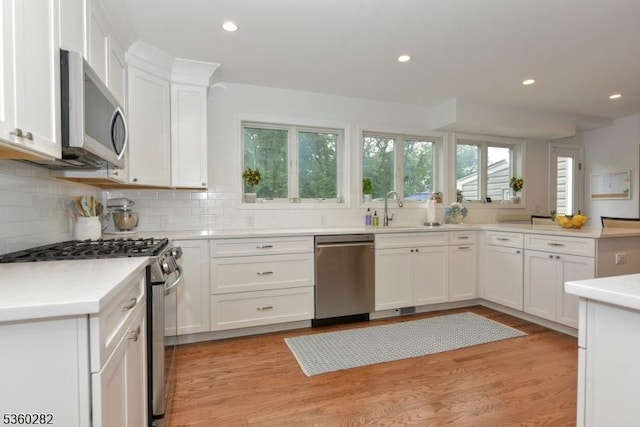 789 Charnwood Dr, Wyckoff Twp, NJ 07481 - kitchen featuring appliances with stainless steel finishes, white cabinetry, decorative backsplash, light countertops, and light wood-style floors