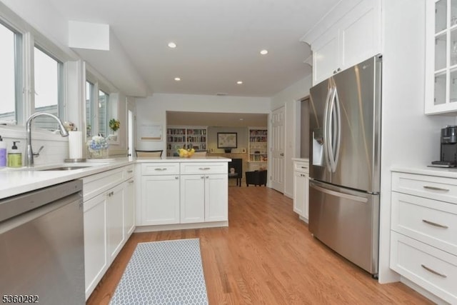 789 Charnwood Dr, Wyckoff Twp, NJ 07481 - kitchen featuring stainless steel appliances, a sink, white cabinetry, light wood-style flooring, and glass insert cabinets