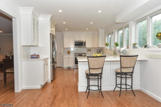 789 Charnwood Dr, Wyckoff Twp, NJ 07481 - kitchen featuring appliances with stainless steel finishes, a peninsula, light countertops, white cabinets, and tasteful backsplash