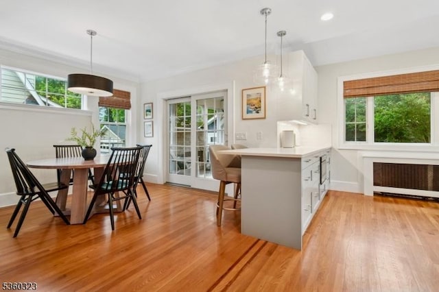 51 S Pierson Rd, Maplewood Twp, NJ 07040 - kitchen featuring radiator, white cabinets, light wood-style flooring, light countertops, and a peninsula