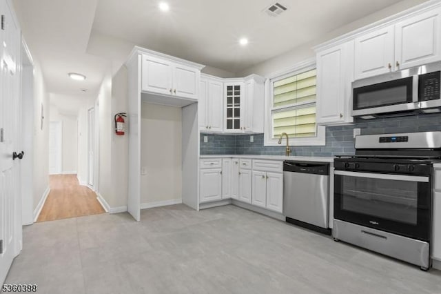 261 22nd St, Irvington Twp, NJ 07111 - kitchen featuring appliances with stainless steel finishes, backsplash, white cabinets, glass insert cabinets, and baseboards