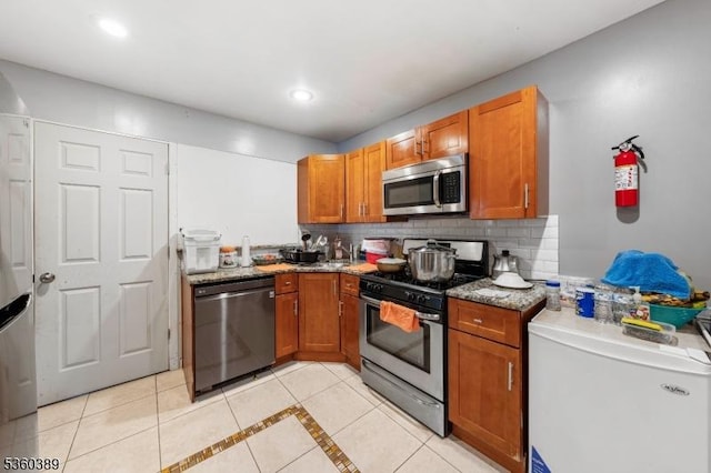 896 Maurice Ave, Rahway City, NJ 07065 - kitchen with stainless steel appliances, light tile patterned floors, tasteful backsplash, light stone countertops, and brown cabinetry