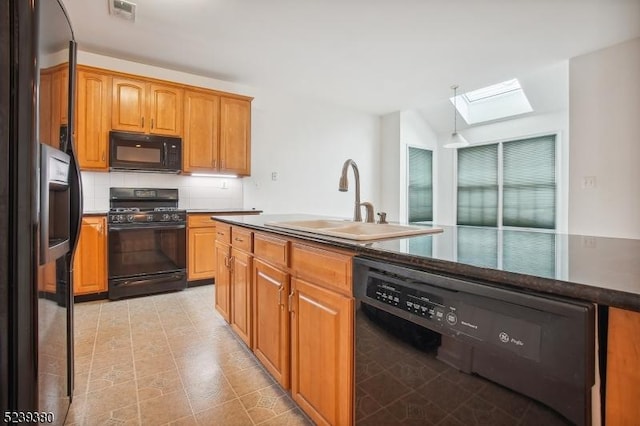 12 Hudson Dr, Bernards Twp, NJ 07920 - kitchen featuring black appliances, a skylight, a sink, dark countertops, and brown cabinetry