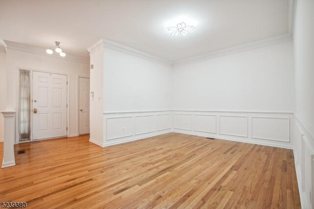 12 Hudson Dr, Bernards Twp, NJ 07920 - unfurnished room featuring crown molding, light wood-style flooring, wainscoting, a chandelier, and a decorative wall