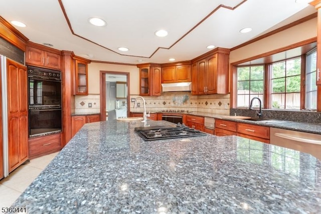 60 Queens Rd, Rockaway Twp, NJ 07866 - kitchen with under cabinet range hood, stainless steel gas stovetop, brown cabinetry, ornamental molding, and dark stone countertops