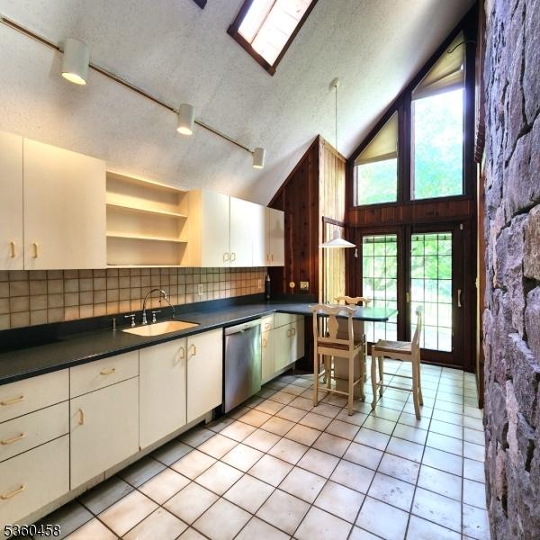 161 Neilson Rd, Wantage Twp, NJ 07461 - kitchen featuring stainless steel dishwasher, dark countertops, a sink, backsplash, and light tile patterned floors