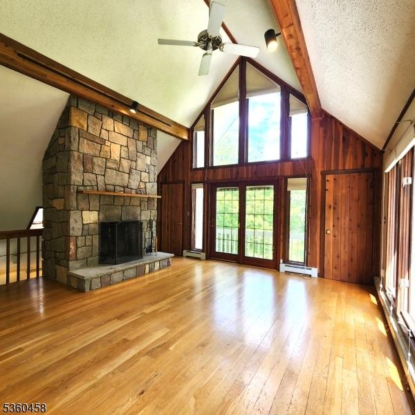 161 Neilson Rd, Wantage Twp, NJ 07461 - unfurnished living room with baseboard heating, plenty of natural light, beamed ceiling, wooden walls, and hardwood / wood-style floors