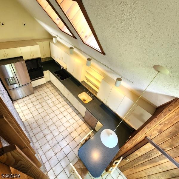 161 Neilson Rd, Wantage Twp, NJ 07461 - kitchen with stainless steel fridge, light tile patterned floors, a textured ceiling, white cabinetry, and black stovetop