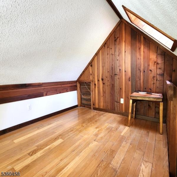 161 Neilson Rd, Wantage Twp, NJ 07461 - additional living space with a skylight, a textured ceiling, vaulted ceiling, hardwood / wood-style floors, and wooden walls