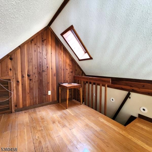 161 Neilson Rd, Wantage Twp, NJ 07461 - bonus room featuring a skylight, vaulted ceiling, hardwood / wood-style floors, a textured ceiling, and wooden walls