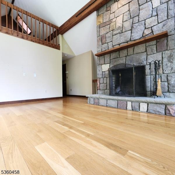 161 Neilson Rd, Wantage Twp, NJ 07461 - unfurnished living room featuring high vaulted ceiling, baseboards, wood finished floors, a stone fireplace, and beamed ceiling