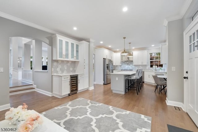 18 Hartley Ln, Bernards Twp, NJ 07920 - kitchen featuring stainless steel refrigerator with ice dispenser, wine cooler, a breakfast bar area, ornamental molding, and tasteful backsplash