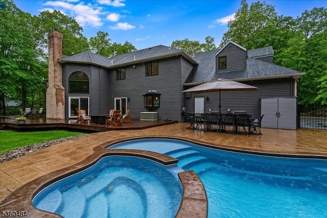 95 Underrock Rd, Sparta Twp, NJ 07871 - back of property featuring a wooden deck, a pool with connected hot tub, a chimney, a patio area, and a shingled roof