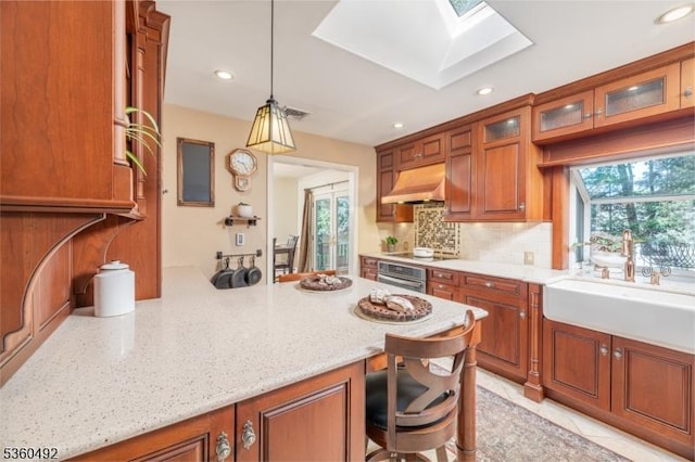 107 Shady Ln, Randolph Twp, NJ 07869 - kitchen featuring under cabinet range hood, a skylight, tasteful backsplash, a breakfast bar, and brown cabinetry