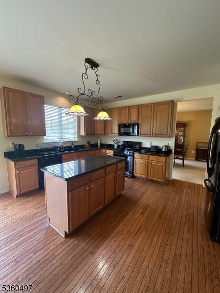 30 Julie Ct, Franklin Twp, NJ 08873 - kitchen with black appliances, dark countertops, wood-type flooring, a kitchen island, and hanging light fixtures