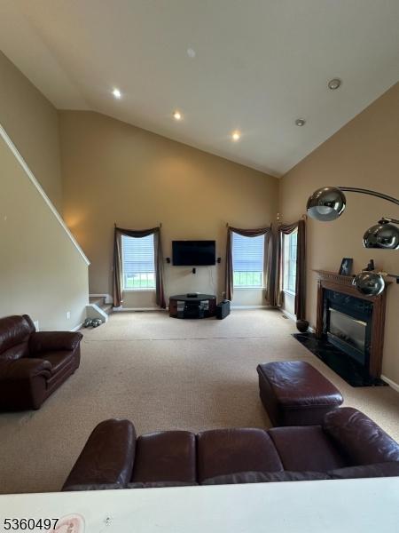 30 Julie Ct, Franklin Twp, NJ 08873 - carpeted living room with high vaulted ceiling, plenty of natural light, a glass covered fireplace, baseboards, and recessed lighting