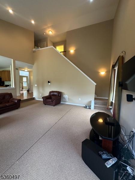 30 Julie Ct, Franklin Twp, NJ 08873 - carpeted living room featuring a high ceiling, baseboards, and stairs