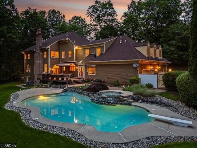10 Beacon Hill Dr, Chester Twp, NJ 07930 - back of property at dusk featuring a deck, an in-ground hot tub, an outdoor pool, and a chimney