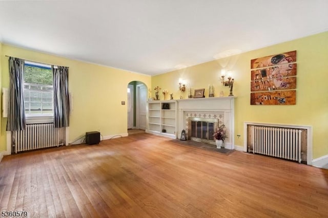 274 Diamond Hill Rd, Berkeley Heights Twp, NJ 07922 - unfurnished living room with radiator heating unit, arched walkways, wood-type flooring, and a fireplace
