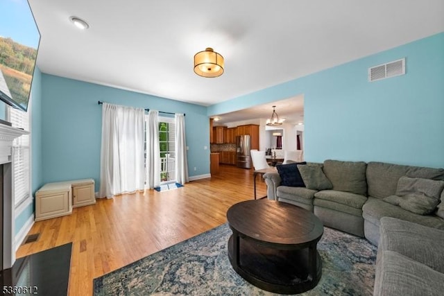 143 Oak St, Bridgewater Twp, NJ 08807 - living area with light wood-type flooring, a glass covered fireplace, a chandelier, and baseboards