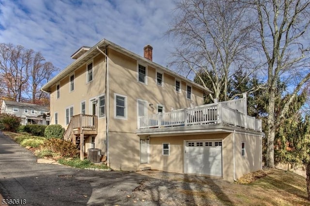 22 Somerset Ave, Bernardsville Boro, NJ 07924 - rear view of house featuring stucco siding, a chimney, driveway, and a garage