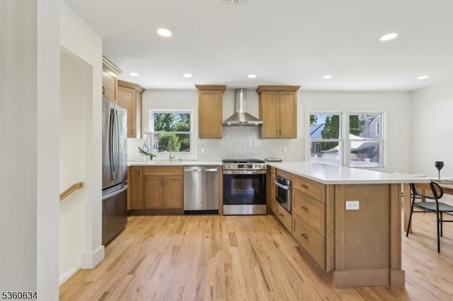 541 Westfield Rd, Scotch Plains Twp, NJ 07076 - kitchen featuring stainless steel appliances, wall chimney range hood, a peninsula, light wood-type flooring, and brown cabinetry