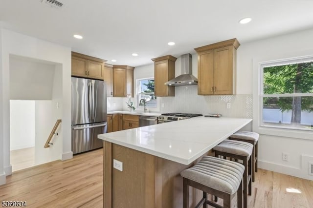 541 Westfield Rd, Scotch Plains Twp, NJ 07076 - kitchen featuring stainless steel appliances, wall chimney exhaust hood, a peninsula, light wood finished floors, and a breakfast bar