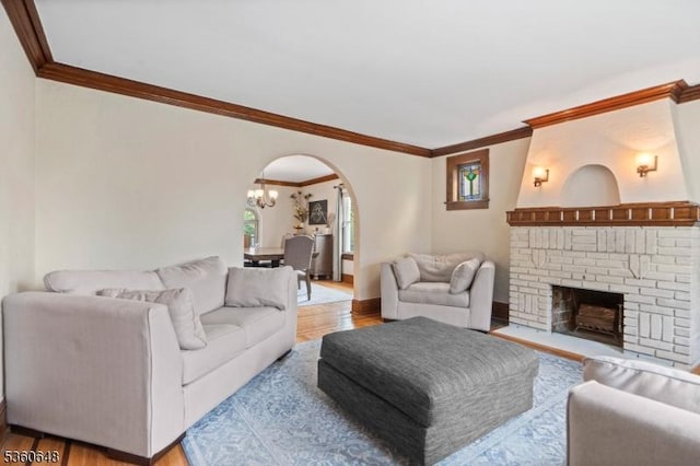 126 Beech St, Nutley Twp, NJ 07110 - living room featuring arched walkways, crown molding, light wood-style floors, a brick fireplace, and a chandelier