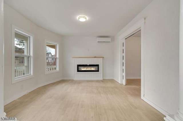 67 Mead St, Newark City, NJ 07106 - unfurnished living room featuring a wall unit AC, light wood-style flooring, a glass covered fireplace, and baseboards