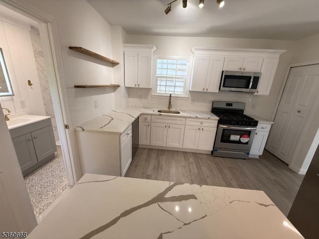 67 Mead St, Newark City, NJ 07106 - kitchen with appliances with stainless steel finishes, a sink, open shelves, light wood-style flooring, and backsplash