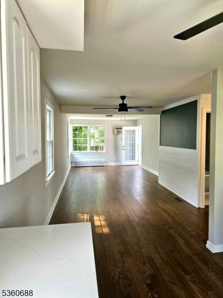 36 Webster Ave, Summit City, NJ 07901 - unfurnished living room featuring dark wood-style flooring, a ceiling fan, baseboards, and a wall unit AC