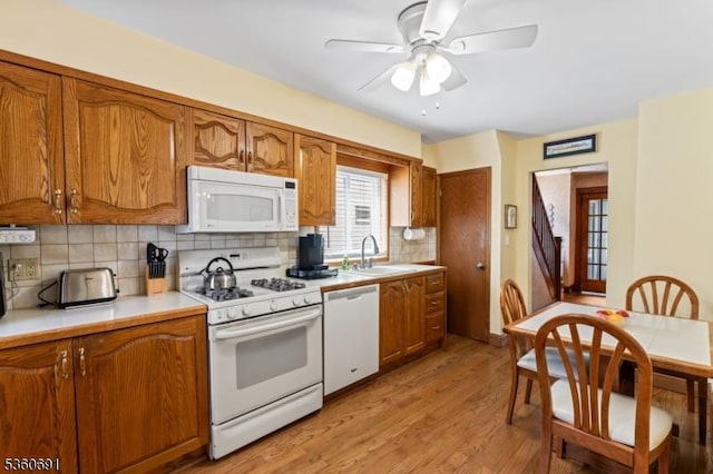 421 Lake Ave, Lyndhurst Twp, NJ 07071 - kitchen featuring white appliances, brown cabinets, a sink, backsplash, and light wood-style flooring