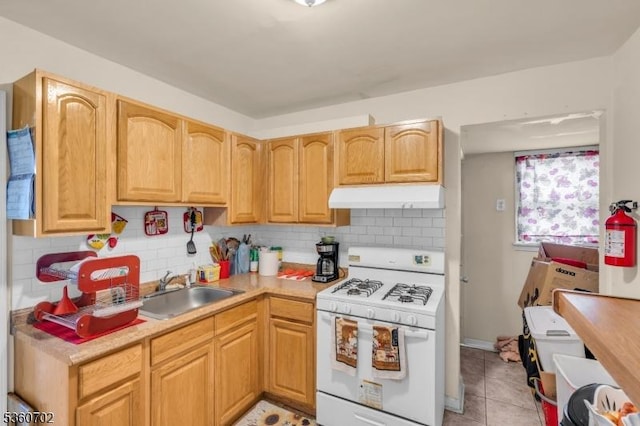 314 Fitzpatrick St, Hillside Twp, NJ 07205 - kitchen featuring white range with gas stovetop, under cabinet range hood, a sink, light countertops, and decorative backsplash