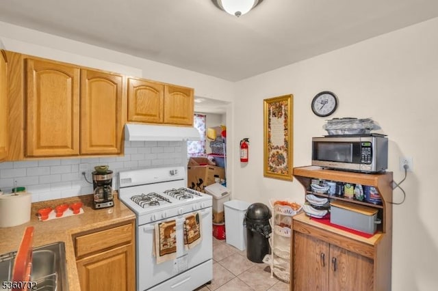 314 Fitzpatrick St, Hillside Twp, NJ 07205 - kitchen with white range with gas stovetop, stainless steel microwave, under cabinet range hood, backsplash, and light tile patterned flooring