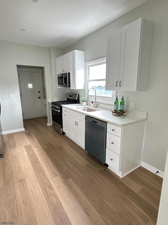 96 Franklin Ave, Maplewood Twp, NJ 07040 - kitchen with stainless steel appliances, a sink, wood finished floors, white cabinets, and light countertops