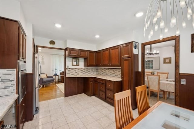 42 Wildwood Ter, Watchung Boro, NJ 07069 - kitchen featuring a chandelier, a wainscoted wall, stainless steel appliances, decorative backsplash, and light tile patterned floors
