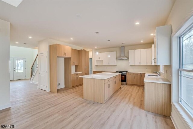 92 Hancock Rd, Piscataway Twp, NJ 08854 - kitchen with wall chimney exhaust hood, a sink, gas stove, a kitchen island, and light wood-style flooring