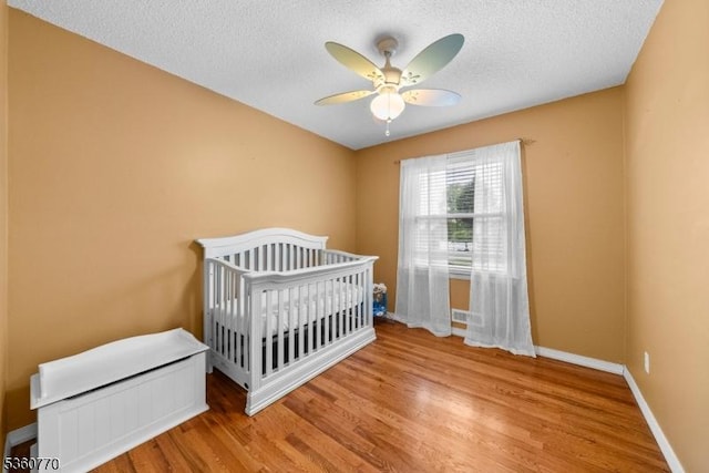 17 4th St, South River Boro, NJ 08882 - bedroom with wood finished floors, a textured ceiling, baseboards, ceiling fan, and a nursery area